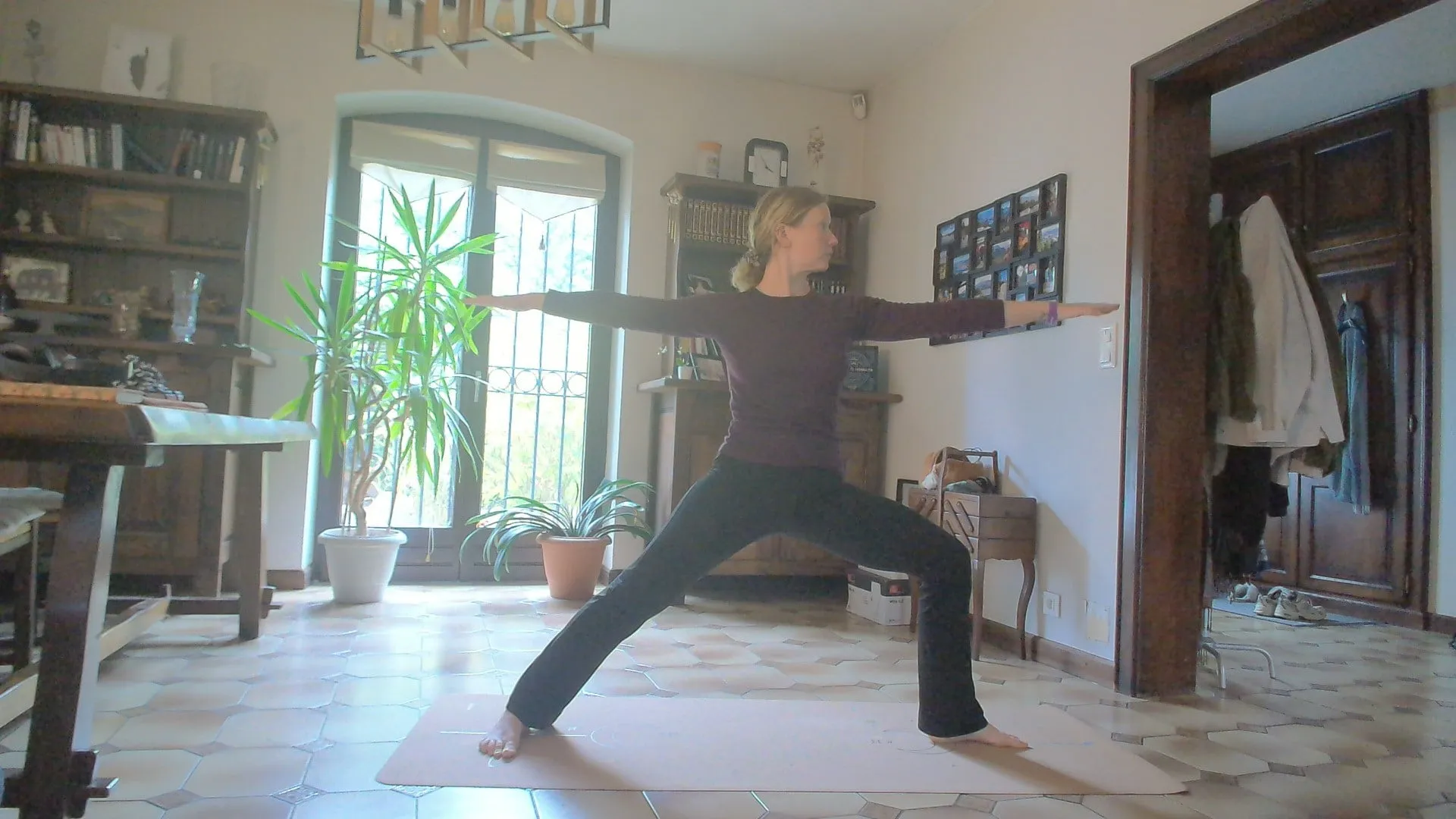 Exemple de placement de la caméra, vu par la webcam d’un ordinateur : Laura en posture du guerrier sur son tapis, chez elle, visible de la tête aux pieds