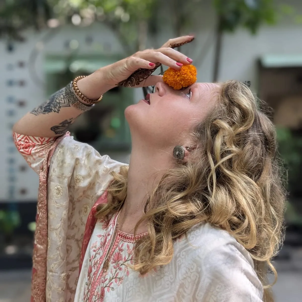 Laura en kurta crème et corail, une fleur d’œillet d’Inde contre le visage